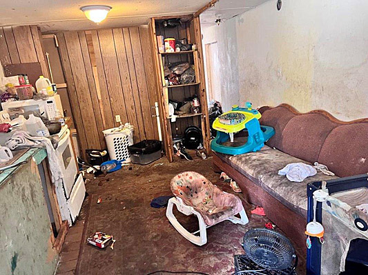 Living area of mobile home with a baby walker on the couch and rocker on the floor